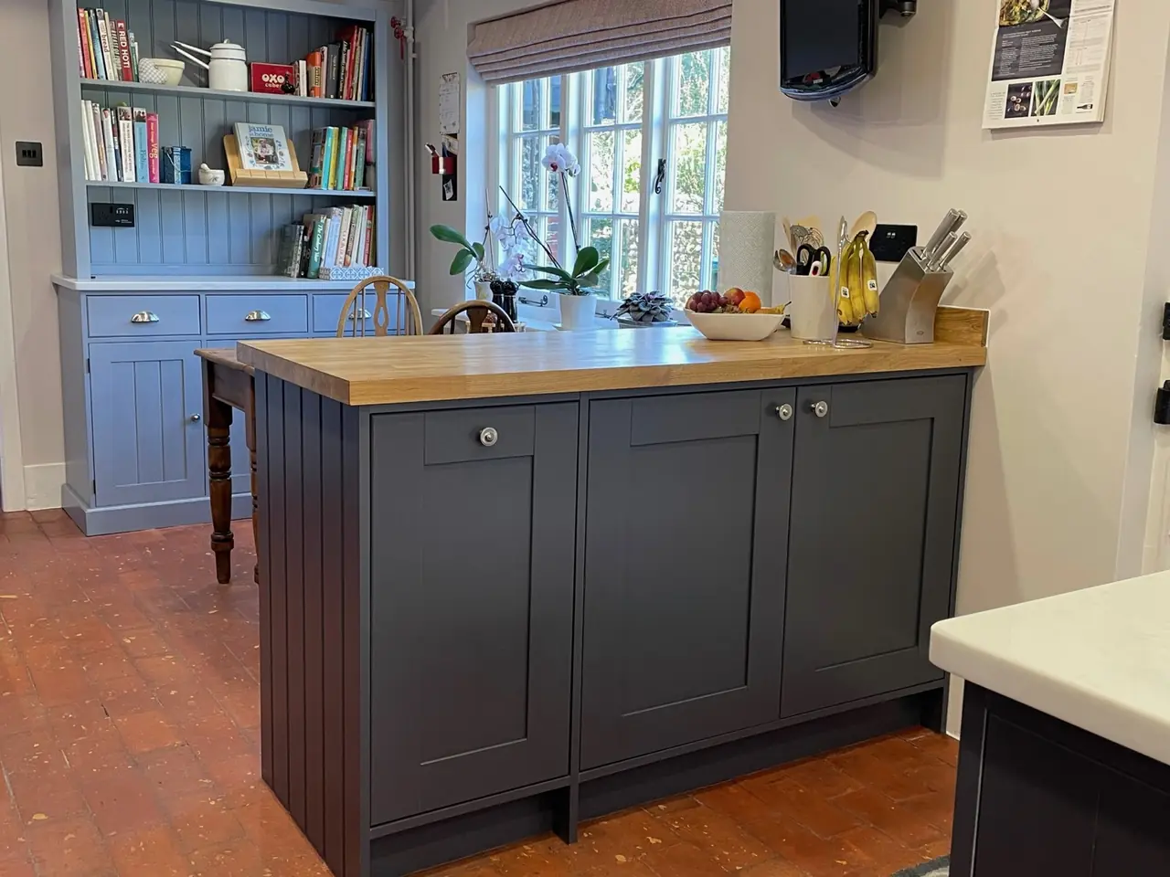 Blue shaker kitchen with a built-in dresser, island and brick floor