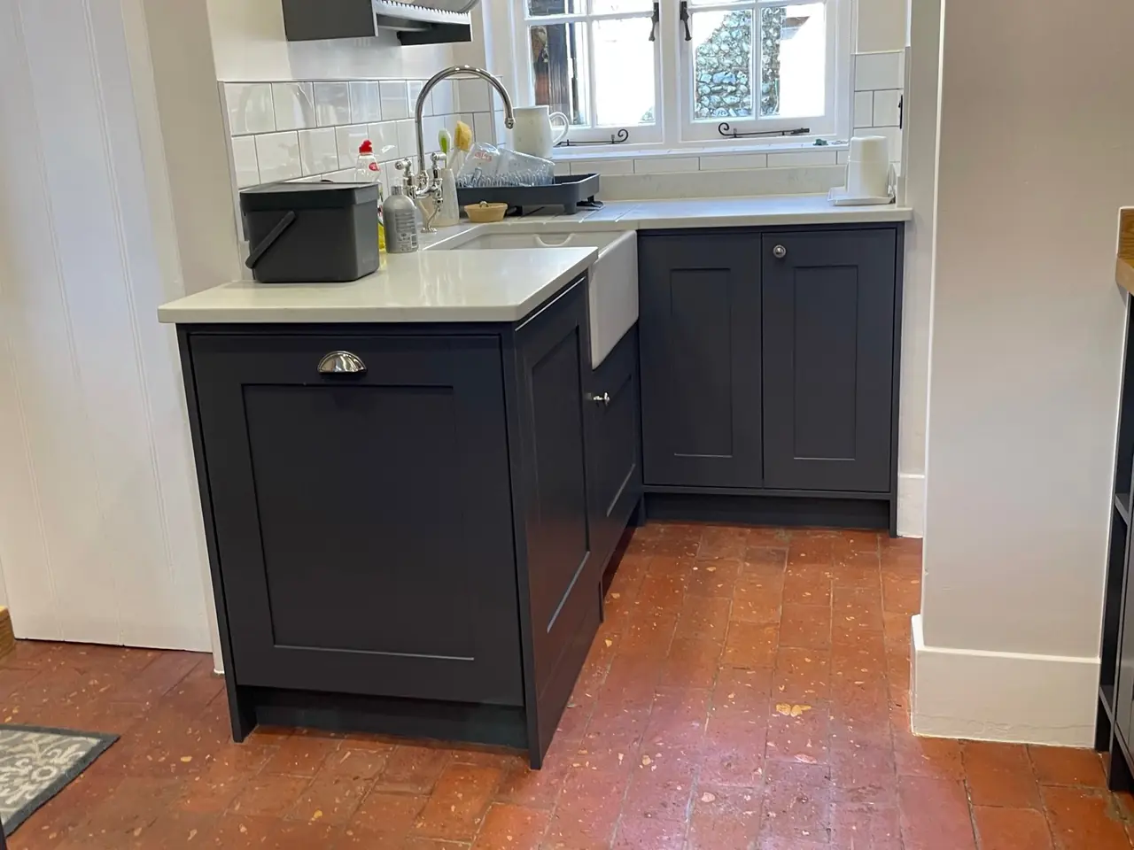 Navy shaker kitchen with a Belfast sink and terracotta tiled floor