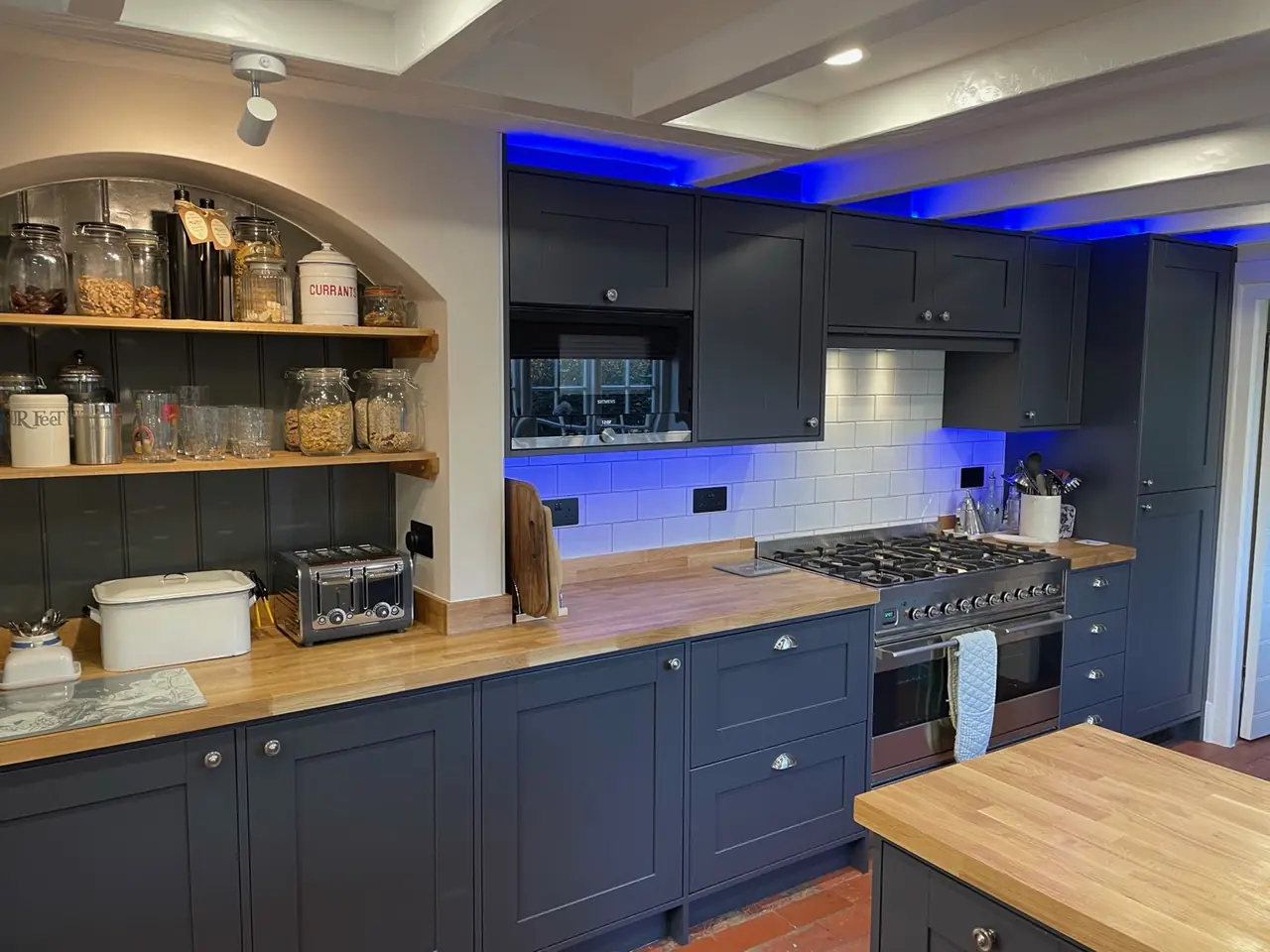 Navy shaker kitchen with solid oak worktops, open shelving and blue LED lighting