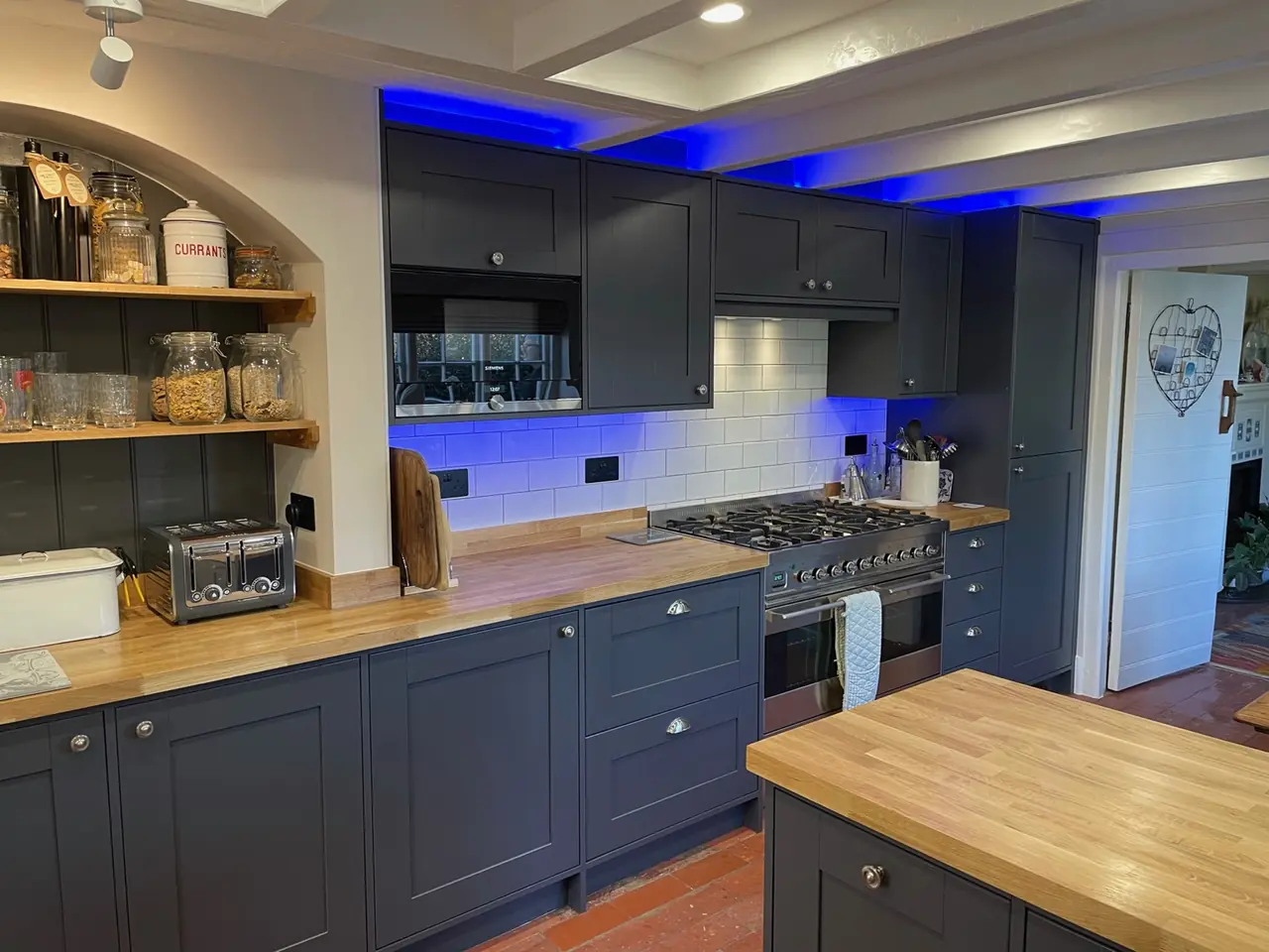 Navy shaker kitchen with oak worktops, a range cooker and blue LED lighting