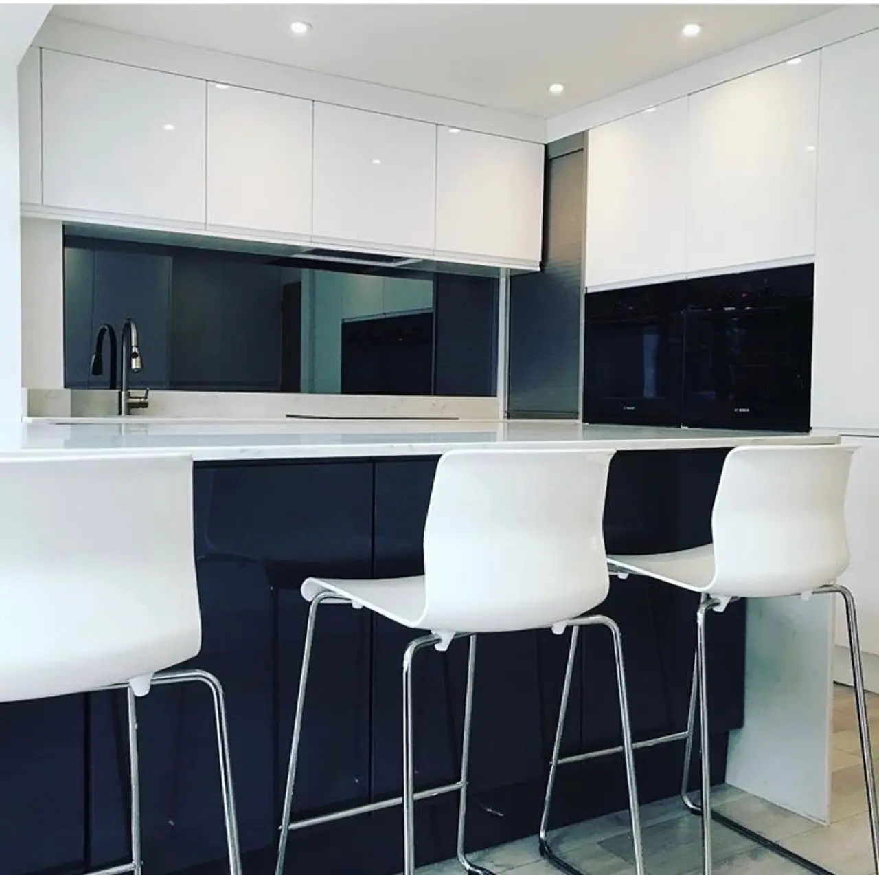 White gloss kitchen with a navy island and bar stools