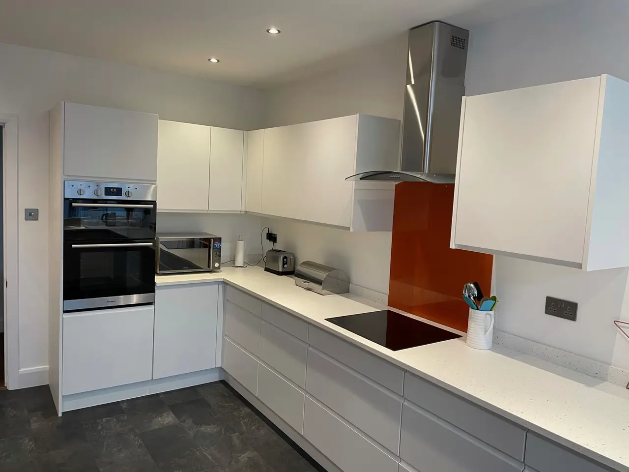 Kitchen white gloss orange glass splashback hob, made and fitted by Sussex Design Interiors
