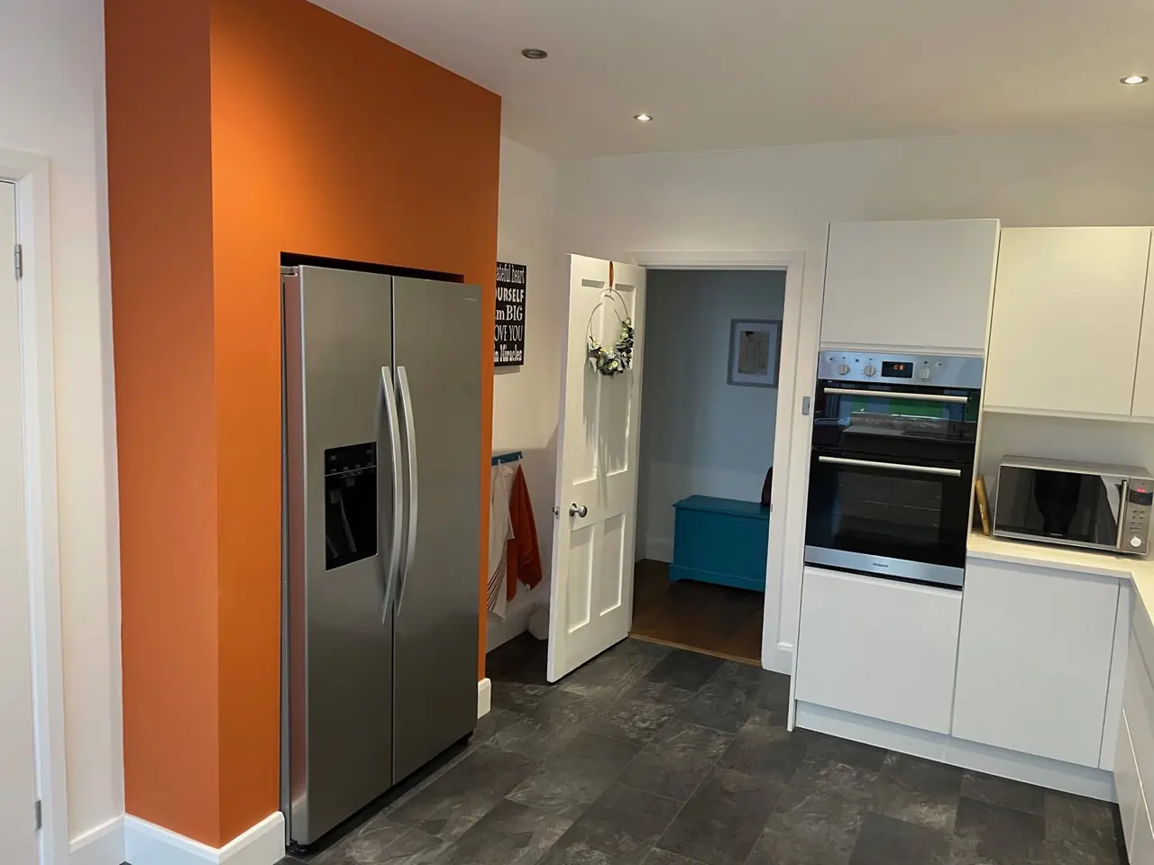 Kitchen white orange accent wall fridge freezer, made and fitted by Sussex Design Interiors