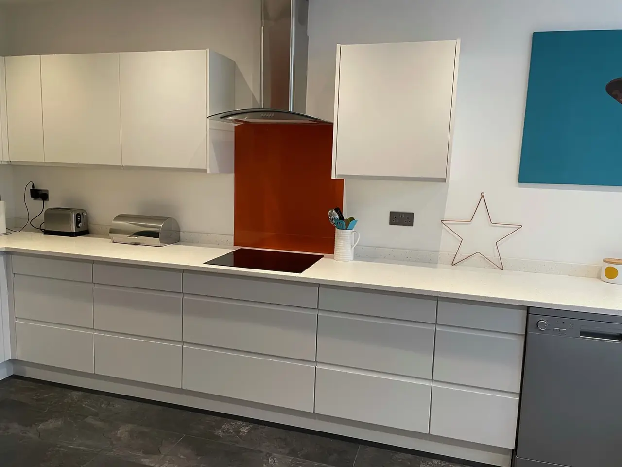 Kitchen white orange glass splashback hob close-up, made and fitted by Sussex Design Interiors