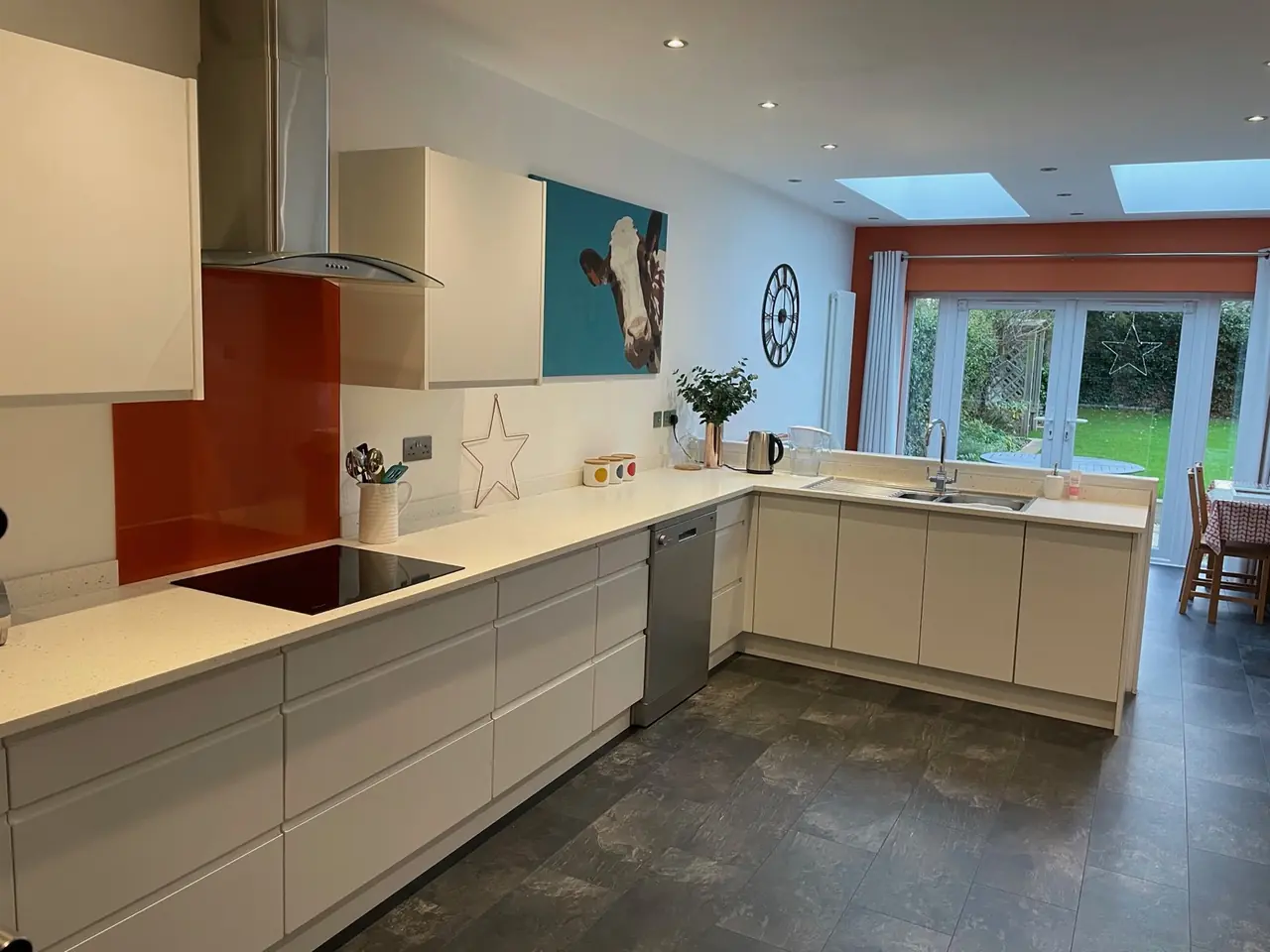 Kitchen white orange splashback garden view, made and fitted by Sussex Design Interiors