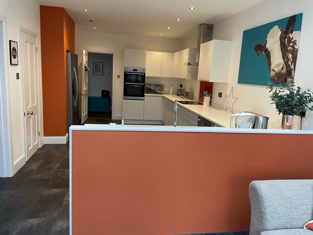 Kitchen white orange wall breakfast bar artwork, made and fitted by Sussex Design Interiors