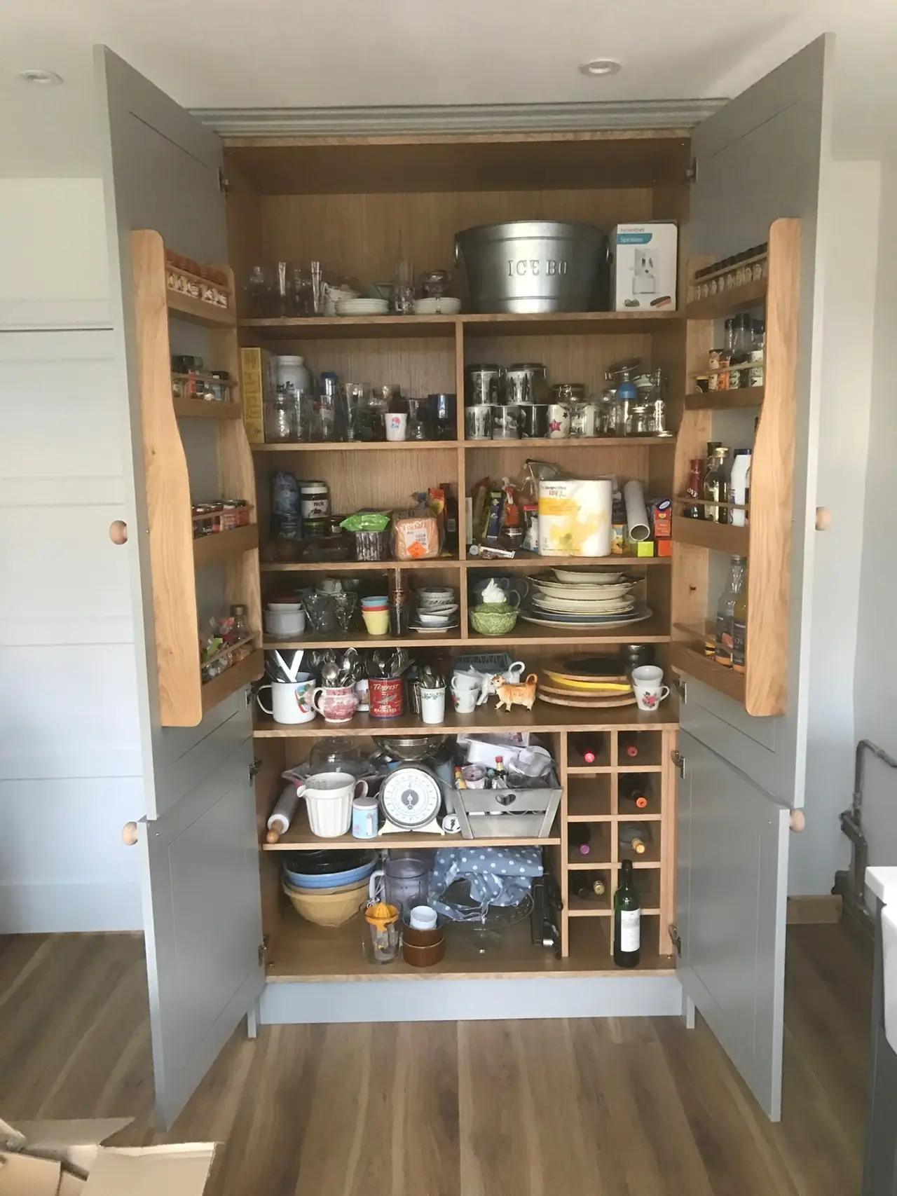 Tall larder cabinet standing open with stocked internal shelves