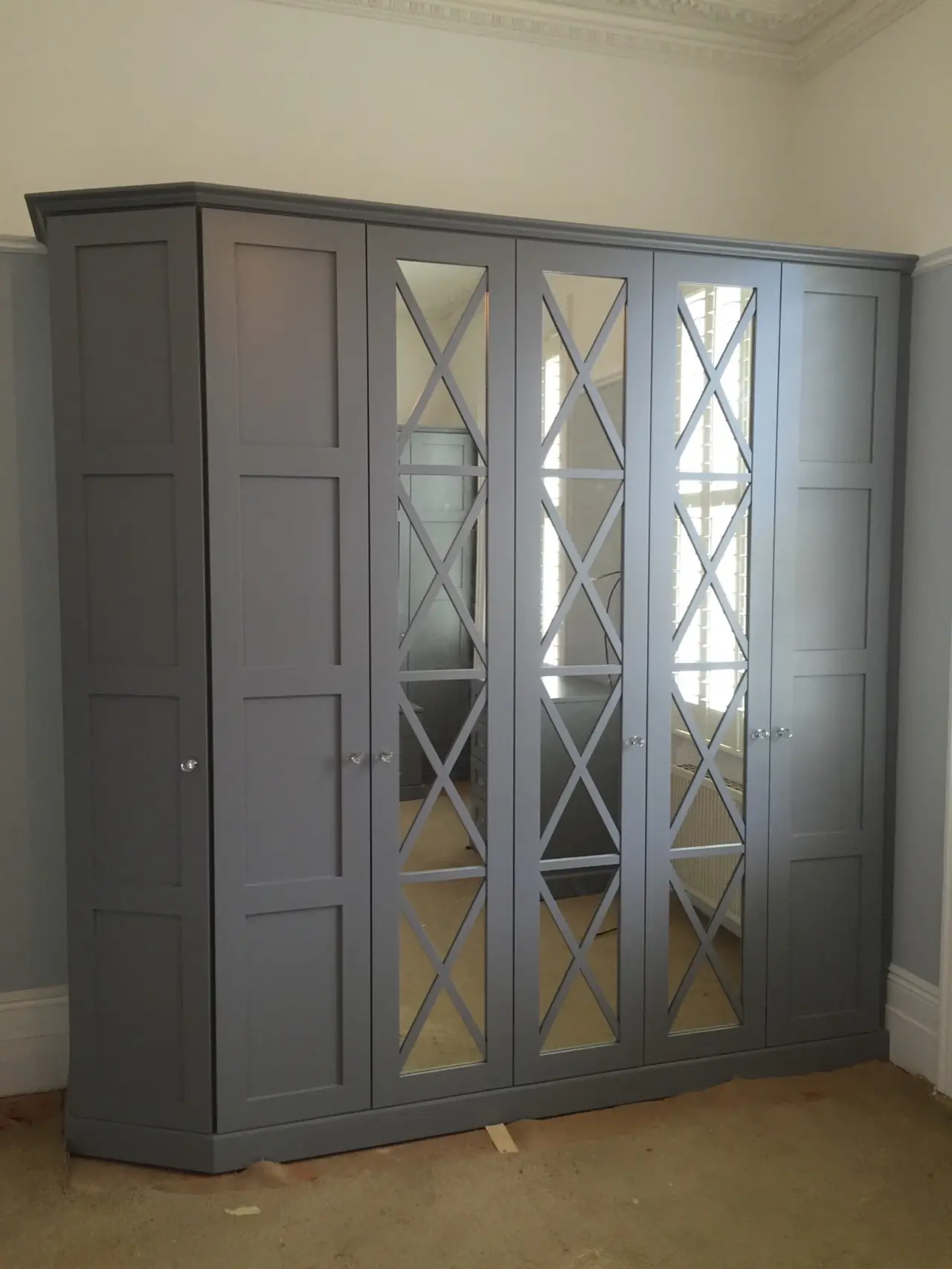 Wardrobe grey mirrored X pattern doors, made and fitted by Sussex Design Interiors