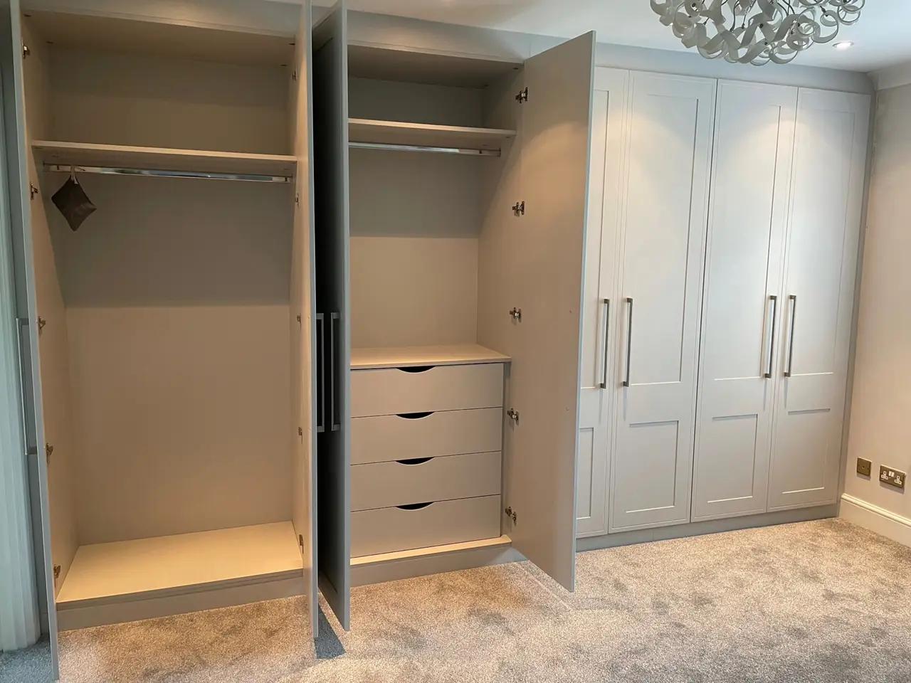 Light grey wardrobe with doors open showing hanging rails and fitted drawers