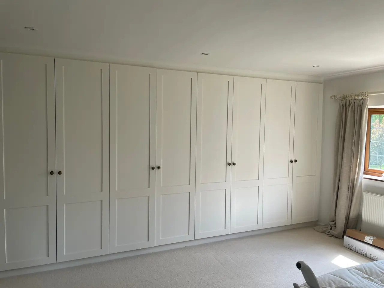White shaker fitted wardrobes running wall to wall in a bedroom