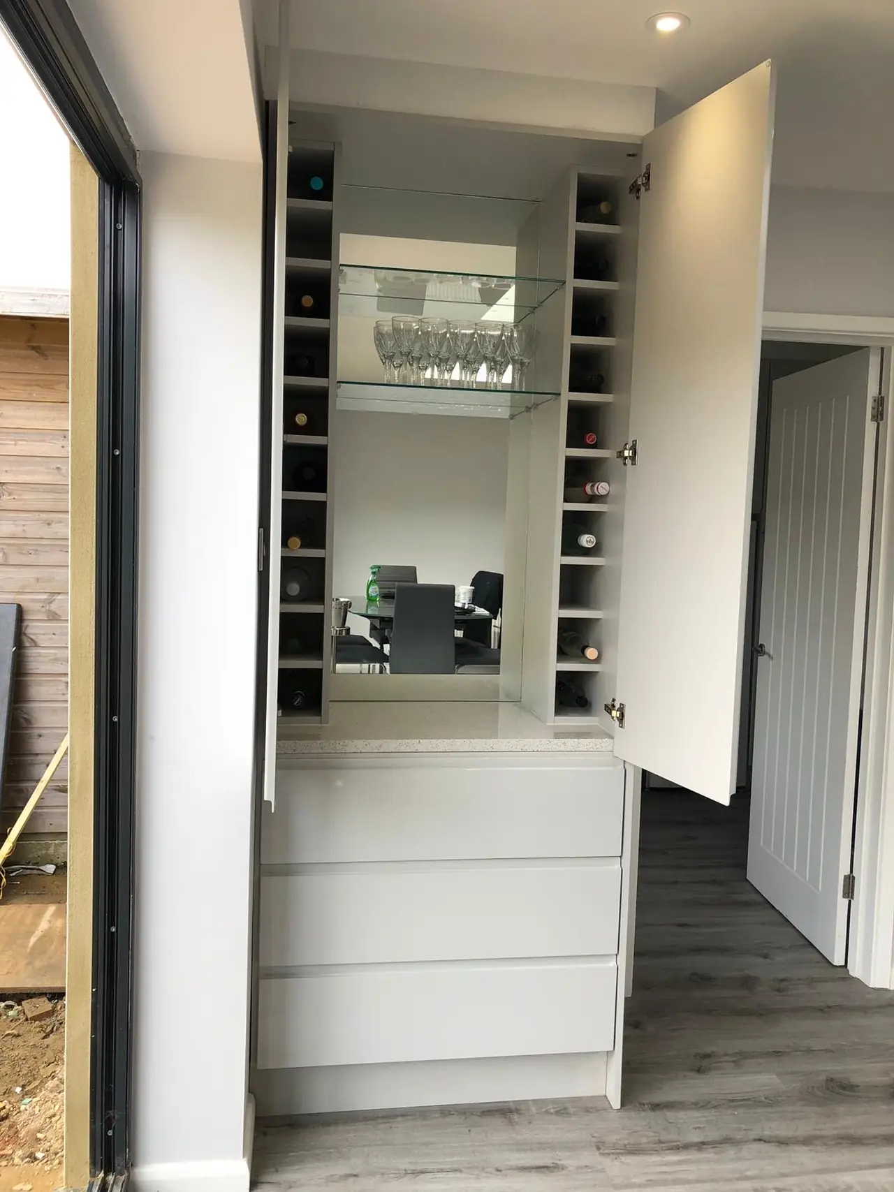 Fitted drinks cabinet with a wine rack, mirrored back panel and gloss drawers, made and fitted by Sussex Design Interiors